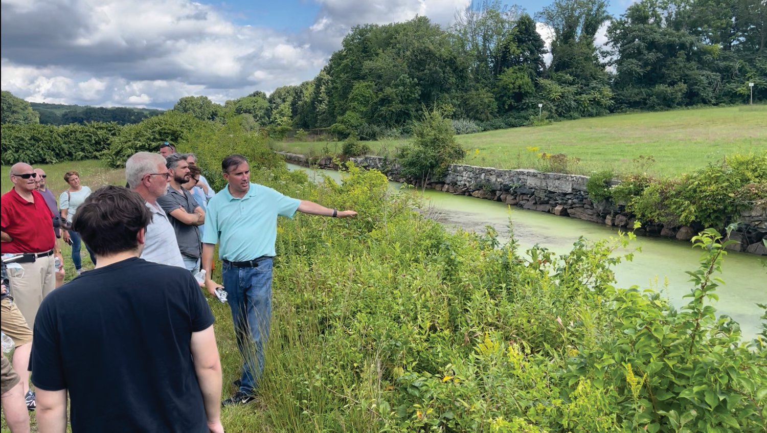 THE CANAL: Chris Reynolds of Brady Sullivan Properties points to the canal that runs south from the Cranston Print Works Pond. Still filled with water, the canal has sat stagnant for years. Addressing its future will require significant discussions with DEM and other entities, Reynolds said